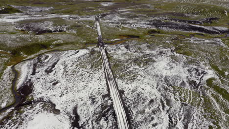 Aerial-follow-of-white-car-driving-on-a-mountain-road-partially-covered-with-snow