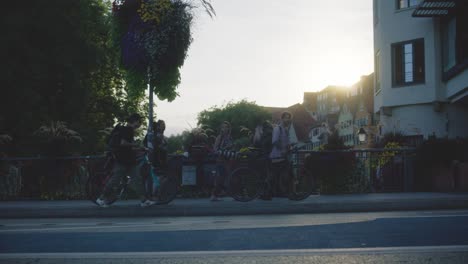 Group-of-People-Pushing-Bikes-in-Tubingen,-Germany-in-4K-Downtown-Home-of-Europes-Oldest-University-At-Sunset