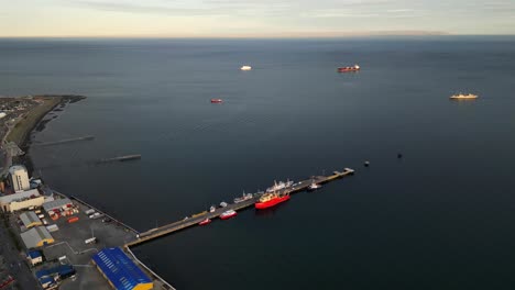 Antarctic-Gateway-Punta-Arenas-Sea-Port-Chilean-Shore-Aerial-Drone-View-Above-Calm-Blue-Water,-Sailing-Ships-and-Skyline-in-Magallanes-Region