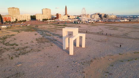 Art-structure-on-the-beach,-celebration-of-500-years-of-Le-Havre,-against-city-skyline