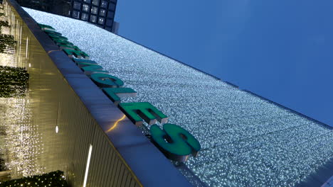 Vertical-low-angle-shot-of-mall-facade-lit-up-for-Christmas,-pan-left