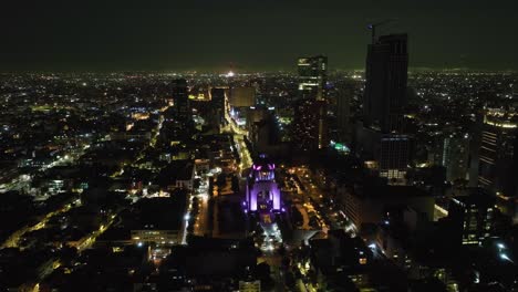 Vista-Aérea-Dando-Vueltas-Alrededor-Del-Monumento-A-La-Revolución-Iluminada,-Noche-En-La-Ciudad-De-México