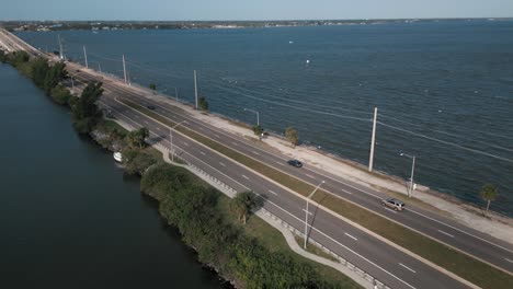 Light-traffic-on-coastal-highway-with-beautiful-water---aerial-drone-tracking-shot