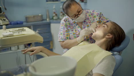 Young-Man-Getting-His-Teeth-Checked-By-a-Dentist