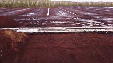 Lateral-aerial-view-revealing-peat-deposit-mine-site-in-middle-of-a-forest
