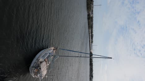 Aerial-shot-flying-past-sailboat-on-peaceful-water---vertical-video