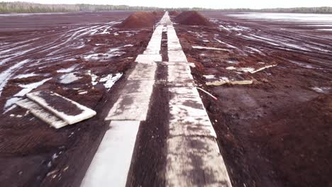 Aerial-view-at-day-time-of-huge-peat-deposit-with-a-wooden-plank-road-running-through-it