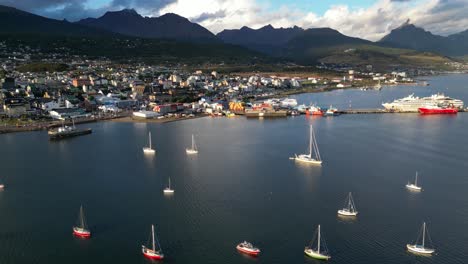 Aerial-Panoramic-Above-Port-of-Ushuaia-Argentina,-Boats-Docked-and-Cityscape-Skyline-in-Calm-Beautiful-Dreamy-Patagonian-Landscape,-Water-Reflection