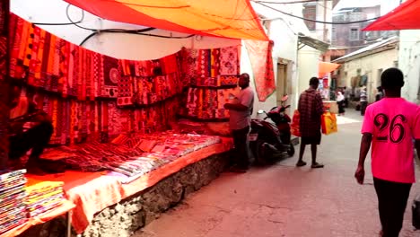 Local-exterior-shops-in-Stone-Town-known-as-Mji-Mkongwe,-people-passing-by