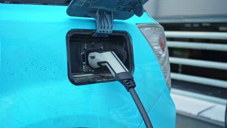 Verkleinern-Sie-Den-Fokus-Auf-Das-Schnelle-Garo-Ladegerät,-Das-An-Ein-Modernes-Neues-Blaues-Elektroauto-Angeschlossen-Ist