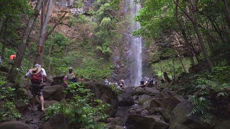 Crowds-of-Hikers-Gather-Underneath-a-Waterfall-in-the-Lush-Foliage-of-the-Forest-on-the-Island-of-Kauai-in-Hawaii