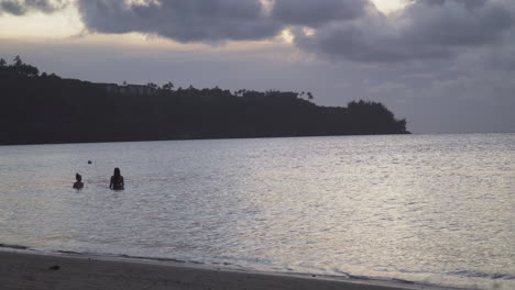 Zwei-Junge-Frauen-Reden-Und-Schwimmen-In-Der-Abenddämmerung-An-Einem-Bewölkten-Abend-An-Einem-Wunderschönen-Strand-Auf-Der-Insel-Kauai-In-Hawaii
