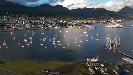 Boats-Docked-in-Ushuaia-Bay,-Argentinian-Patagonic-Landscape,-Aerial-Drone-View-Above-Dreamy-South-American-Landscape-of-Subpolar-Weather,-City-and-Mountain-Range