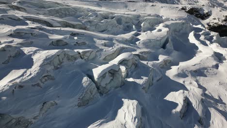 Aerial-view-of-a-glacier-in-the-Swiss-alps-in-winter,-relief-and-shadows,-snow-covered-ground
