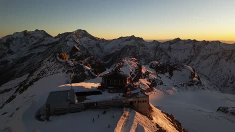 aerial,-sunrise-in-the-alps,-snowy-mountains-in-winter,-warm-sky,-seas-fee
