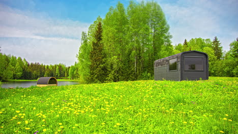 Timelapse-of-a-green-meadow-with-flowers,-trees-and-a-wooden-cabin,-over-which-time-and-clouds-pass-at-high-speed