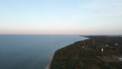 Paragliding-over-Baltic-Sea-coast-at-calm-pastel-blue-evening,-aerial-view