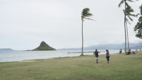 A-Couple-of-tourist-Sightseeing-The-Island-of-Miokoli'i-Also-Known-as-Chinaman's-Hat-on-a-Windy-Day-on-Oahu-in-Hawaii