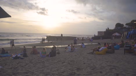 Crowds-relaxing-by-the-beach-at-sunset-on-Batu-Bolong-beach,-Bali-Canggu