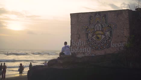 A-man-sits-by-the-cliff-at-the-famous-Batu-Bolong-beach-in-Bali-Canggu