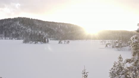 Helle-Sonne-Scheint-Im-Winter-über-Die-Berge,-Den-Zugefrorenen-See-Und-Die-Hütte