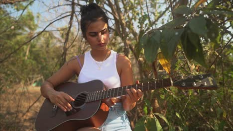 Indisches-Mädchen,-Das-Während-Des-Sonnenuntergangs-Inmitten-Einer-Grünen-Wiese-Gitarre-Spielt