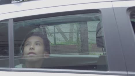 La-Familia-Llega-En-Coche-A-Su-Destino,-El-Coche-Se-Detiene-Y-Un-Niño-Mira-Por-La-Ventana-Mientras-Levanta-La-Mano-Hacia-El-Cristal