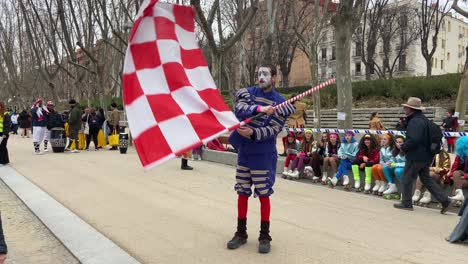 Static-view-of-a-costumed-acrobat-in-the-street-waving-and-waving-a-red-and-white-chequered-flag