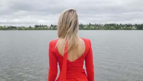 Blonde-woman-in-red-dress-standing-on-the-seashore