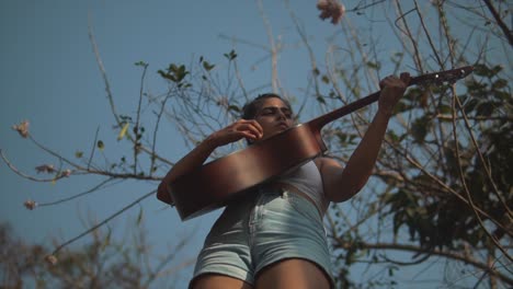 Tiefaufnahme-Eines-Indischen-Mädchens,-Das-Unter-Einem-Baum-Gitarre-Spielt