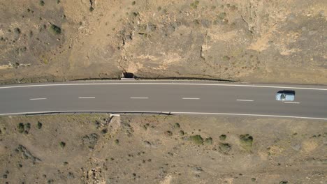 Small-car-moving-on-road-besides-a-cliff-in-Grietas-Lanzarote