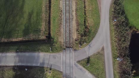 Drone-shot-of-car-going-over-railway-crossing-with-landscape