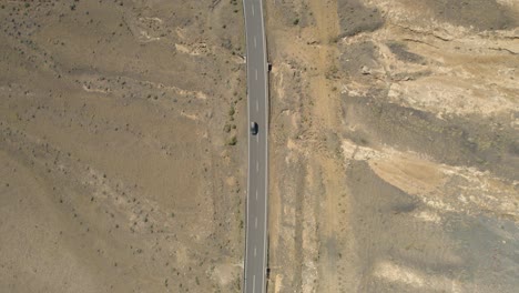 Car-driving-on-a-road-in-Lanzarote,spain-with-sand-on-both-sides-of-the-road