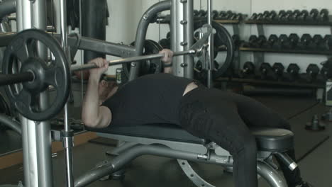 Ancho-De-Un-Hombre-Joven-Usando-Un-Banco-De-Prensa-En-El-Gimnasio