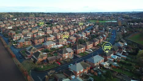 Green-electric-car-charging-symbols-flashing-above-rural-British-neighbourhood-houses,-Aerial-view-descending