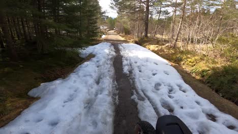 Mountain-bike-tour-at-high-speed-in-beautiful-Norwegian-nature,-with-snow-on-a-narrow-path