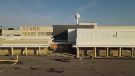 Main-entrance-of-SEARS-retailer-abandoned-store-building,-aerial-fly-back-view