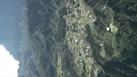 Video-Vertical-Sin-Graduar-De-Un-Dron-Que-Vuela-Hacia-El-Cráter-De-Un-Volcán-Gigante-Con-Casas-Y-Pequeños-Pueblos