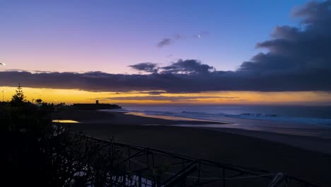 Lebhaft-Violetter-Violetter-Sonnenaufgang-über-Dem-Entspannungsstrand-Mit-Einigen-Wellen-In-Portugal
