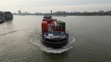 Aerial-Tracking-shot-of-Themhof-vessel-in-Dordrecht,-Netherlands-during-golden-hour-with-cargo