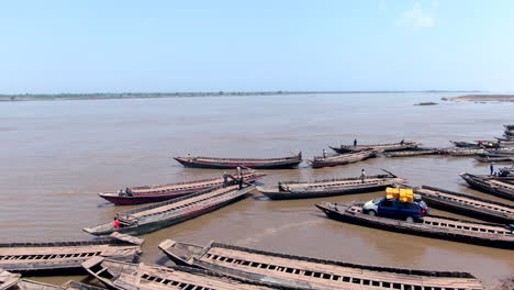 Car-on-a-handmade,-long,-wooden-ferry-raft-in-Nigeria-to-transport-it-across-the-Benue-River---aerial