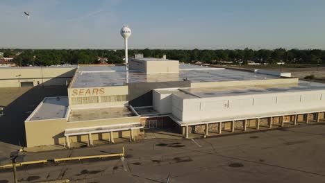 Closed-Sears-Store-with-water-tower-in-Michigan,-aerial-drone-view