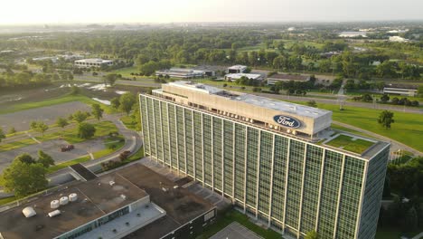 Green-landscape-and-Ford-Motors-office-building-on-sunny-day,-aerial-orbit-view