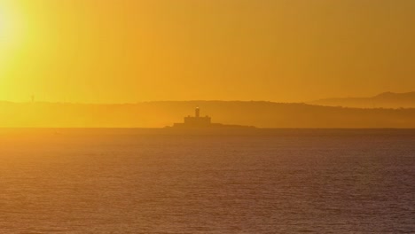 wide-and-amazing-view-of-Bugio-lighthouse-with-huge-sunrise,-on-a-rocky-island,-on-the-atlantic-ocean,-on-a-sunny-day,-near-the-Oeiras-coast-and-Tejo-river,-in-Lisbon,-Portugal