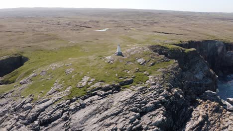 Point-of-interest-drone-shot-of-a-cliffside-lighthouse-with-peat-banks-and-moorland-in-the-background