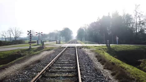 Low-drone-shot-following-railroad-with-crossing-through-nature
