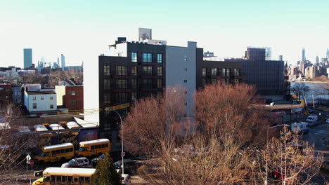 Aerial-view-over-leafless-trees,-towards-a-apartment-building,-spring-sunset-in-Queens,-NY