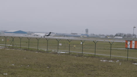 Slow-motion-wide-shot-of-airplane-landing-on-runway-at-airport-during-cloudy-day