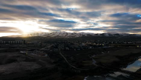 Golden-sunset-above-the-snowy-mountains-with-an-idyllic-community-in-the-valley---aerial-hyper-lapse