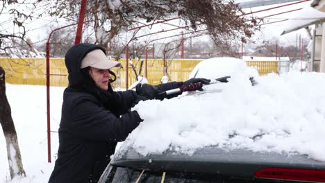 Frau-Entfernt-Schnee-Mit-Schneebesen-Vom-Fahrzeug---Nahaufnahme